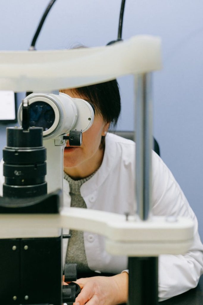 A female scientist focuses through a microscope in a laboratory setting, analyzing samples.